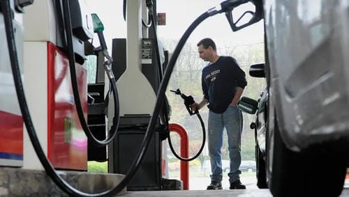 A person holding a fuel nozzle at a gas station.
