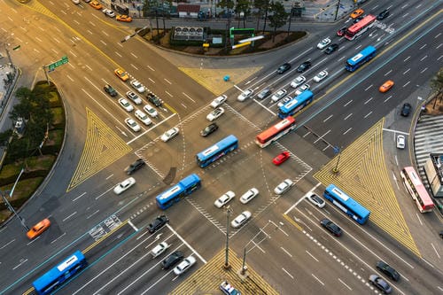 A high-angle shot of a complex, multi-lane city intersection filled with cars, buses, and other vehicles navigating the crossroads.