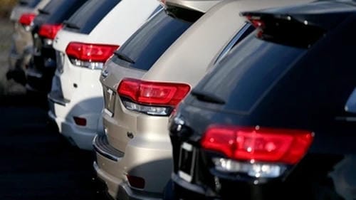 A row of SUVs lined up in a dealership parking lot, viewed from the rear.