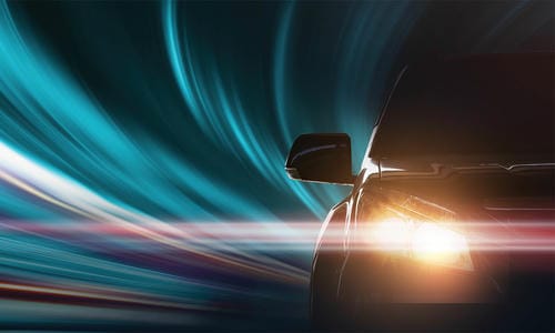 A car driving at night with motion-blurred light trails in the background.
