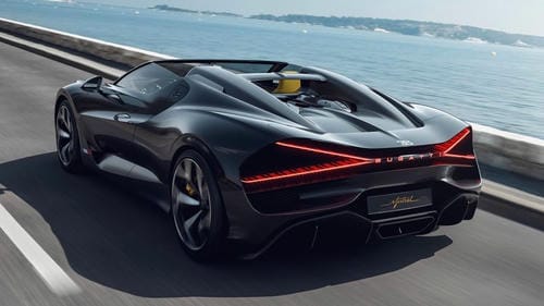 A black convertible Bugatti hypercar driving along a coastal road.