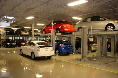 A multi-level indoor car lot with mechanical lifts, showing cars parked on stacked platforms to maximize space.